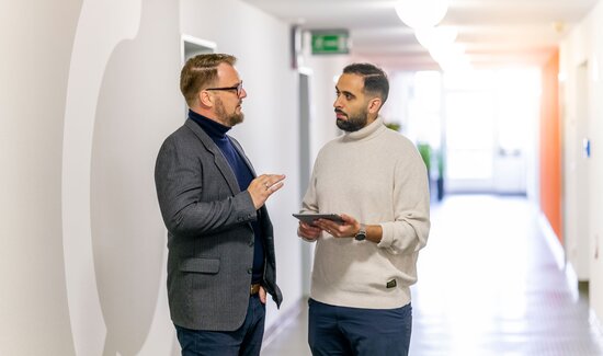 Zwei Kollegen besprechen, wie sie mit dem Managed Service den Anfrage- und Bestellprozess für Kunden optimieren und Kosten sparen.